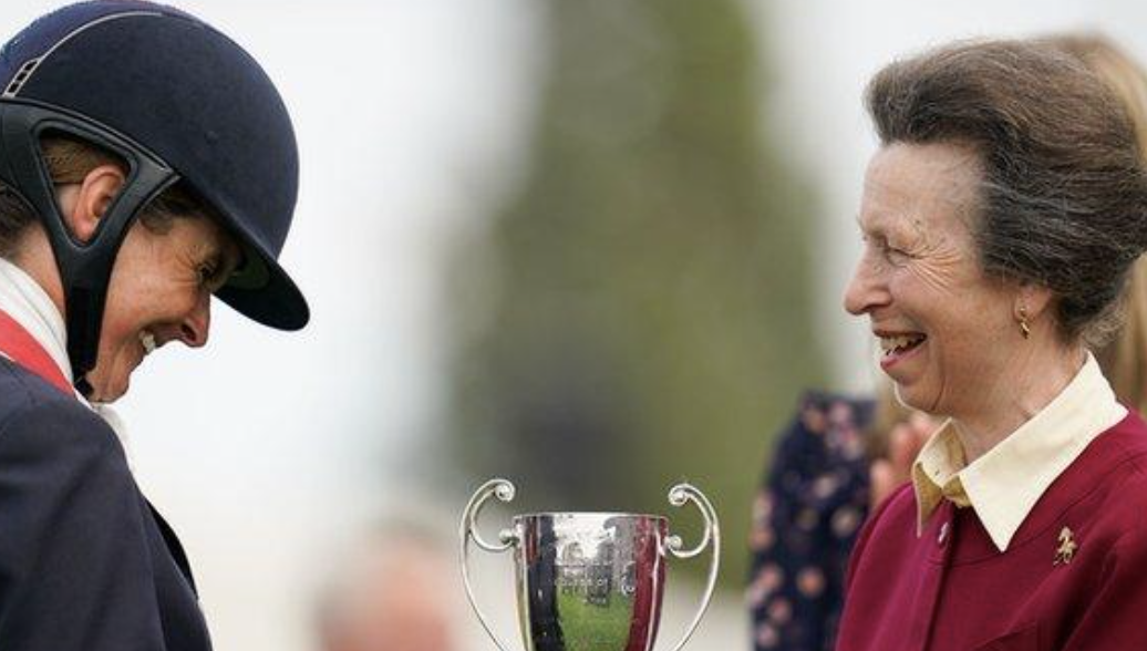 Princess Anne and an equestrian rider admiring a silver Burghley trophy