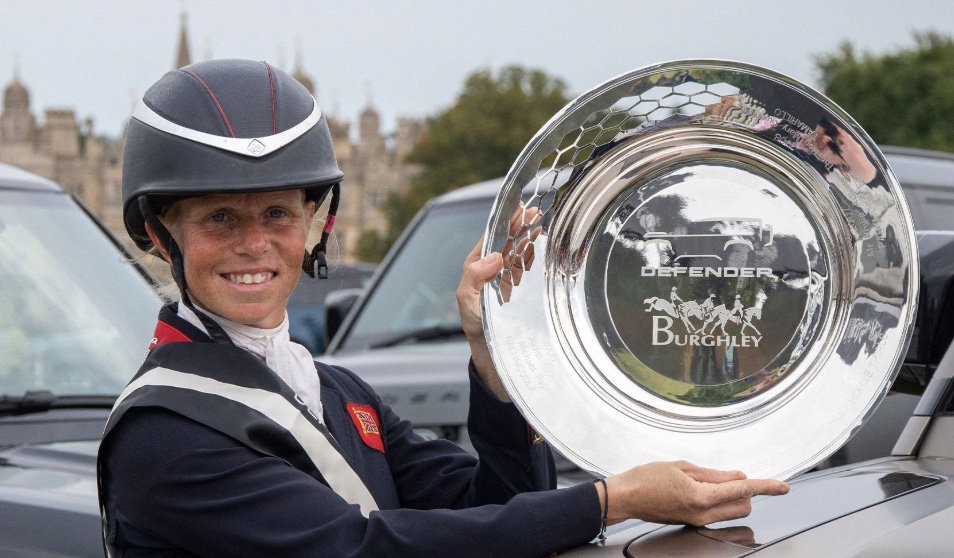 An equestrian rider holding the engraved Burghley trophy plate